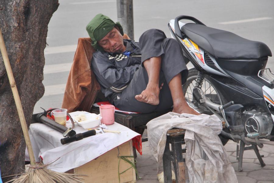 Wer keine Arbeit hat- und das sind viele in Vietnam- der macht auch gleich einmal ein Schläfchen auf dem Fußweg an der Straßenkreuzung am Fußgängerüberweg.
