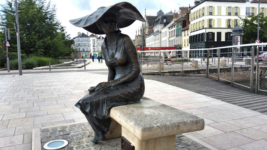 Die ruhige, nachdenkliche Pose der Frau auf der Bank lädt Passanten zum Verweilen und Nachdenken ein. 
