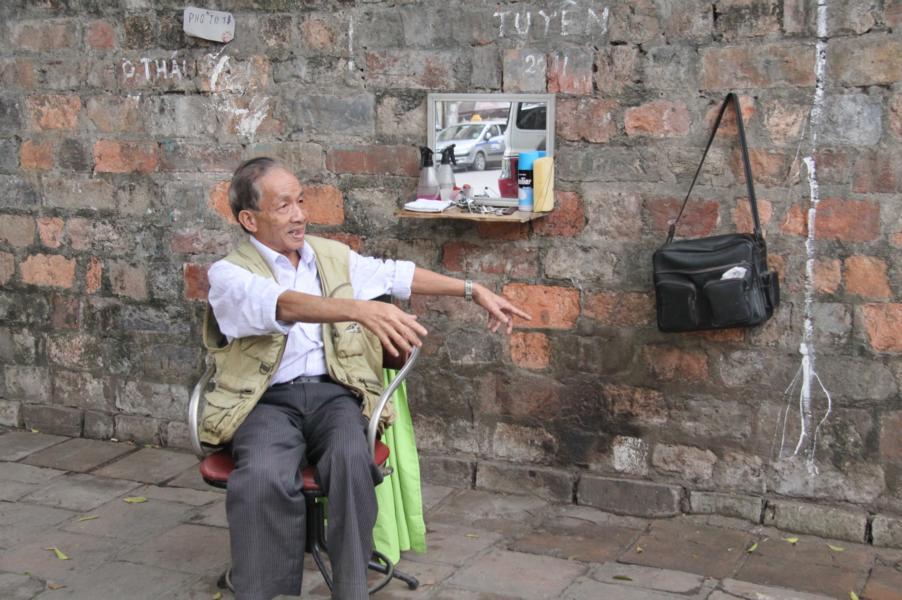 An den Außenmauern der Tempelanlage haben Friseure ihre Stühle aufgebaut , um für ein paar Dong, das ist die vietnamesische Währung (1 ? entspricht 29.353 Dong) ihre Dienste anzubieten.