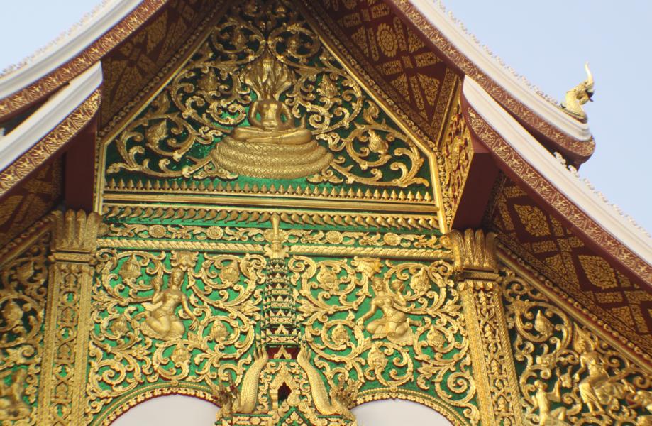 Auf grünem Untergrund sind an der Giebelseite vergoldete Reliefs mit Inhalten aus der buddhistischen Religion angebracht .