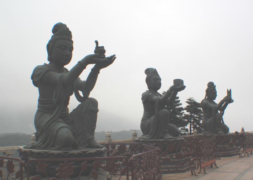 Die Buddhastatue ist von acht kleineren Bronzestatuen umgeben, die Götter oder Unsterbliche darstellen und in den Händen jeweils verschiedene symbolische Gegenstände in Richtung des Buddhas hochhalten.